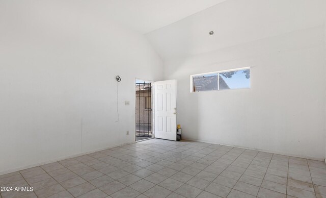 empty room with light tile patterned flooring and high vaulted ceiling