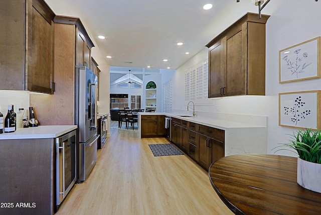 4039 E Paradise Dr, Phoenix, AZ 85028 - kitchen with stainless steel appliances, a sink, beverage cooler, light wood-type flooring, and light countertops
