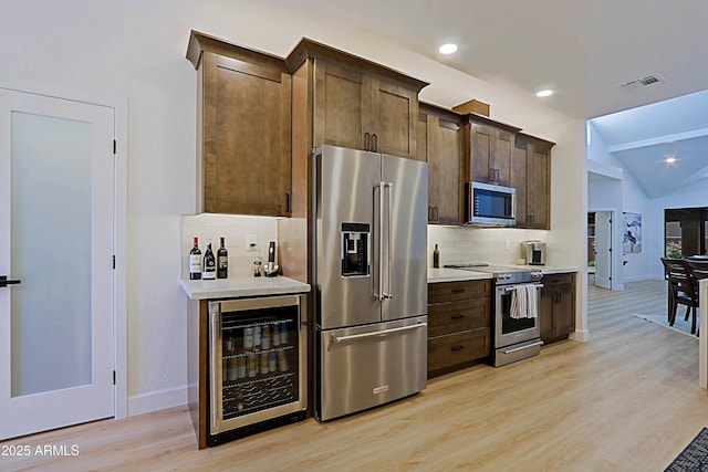 4039 E Paradise Dr, Phoenix, AZ 85028 - kitchen featuring appliances with stainless steel finishes, wine cooler, decorative backsplash, dark brown cabinets, and light wood-style flooring