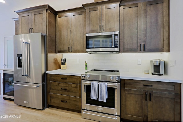 4039 E Paradise Dr, Phoenix, AZ 85028 - kitchen featuring appliances with stainless steel finishes, beverage cooler, light wood-style floors, and decorative backsplash