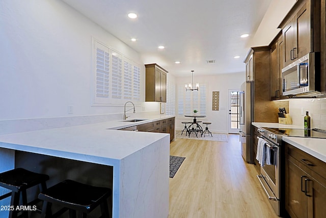 4039 E Paradise Dr, Phoenix, AZ 85028 - kitchen with appliances with stainless steel finishes, a sink, a chandelier, light wood-style floors, and recessed lighting