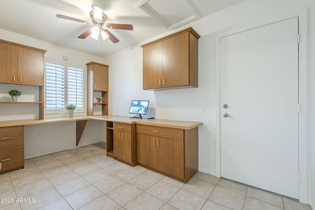 kitchen featuring brown cabinetry, a ceiling fan, open shelves, built in desk, and light countertops