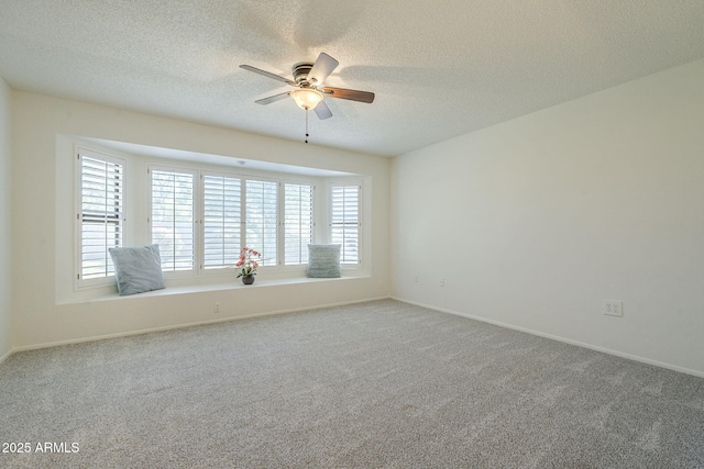 empty room featuring carpet floors, a ceiling fan, a textured ceiling, and baseboards
