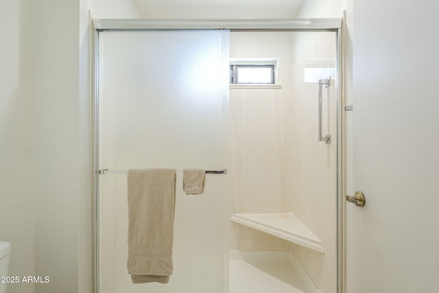 bathroom featuring toilet and a shower stall