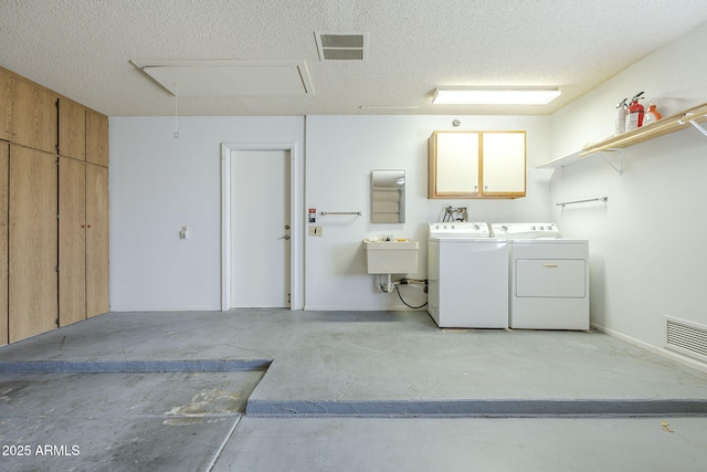 laundry area featuring visible vents, attic access, a textured ceiling, and washer and clothes dryer
