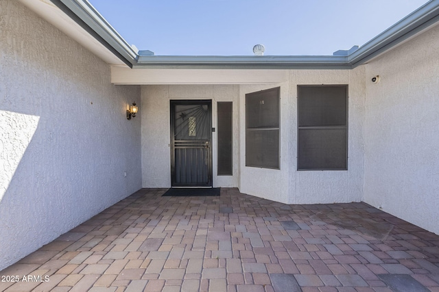 property entrance with a patio and stucco siding