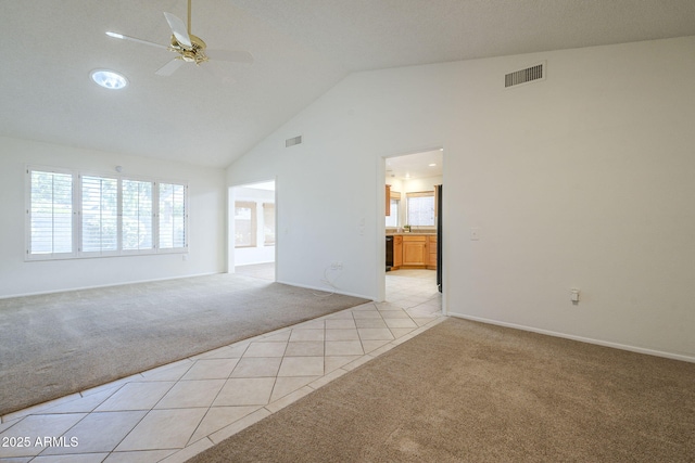 unfurnished living room with a ceiling fan, visible vents, light colored carpet, high vaulted ceiling, and light tile patterned flooring