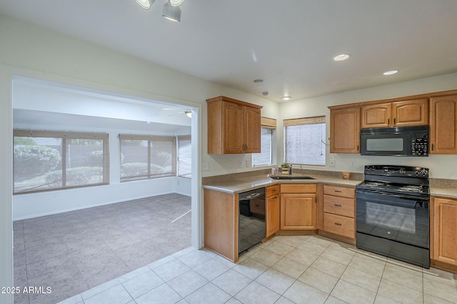 kitchen with a sink, light countertops, light tile patterned floors, black appliances, and recessed lighting