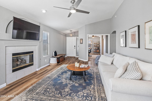 living room featuring a tile fireplace, ceiling fan, hardwood / wood-style floors, and lofted ceiling