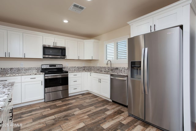 kitchen with dark wood-type flooring, appliances with stainless steel finishes, sink, and white cabinetry