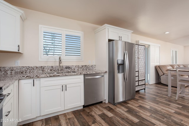 kitchen with white cabinets, appliances with stainless steel finishes, sink, dark hardwood / wood-style floors, and light stone counters