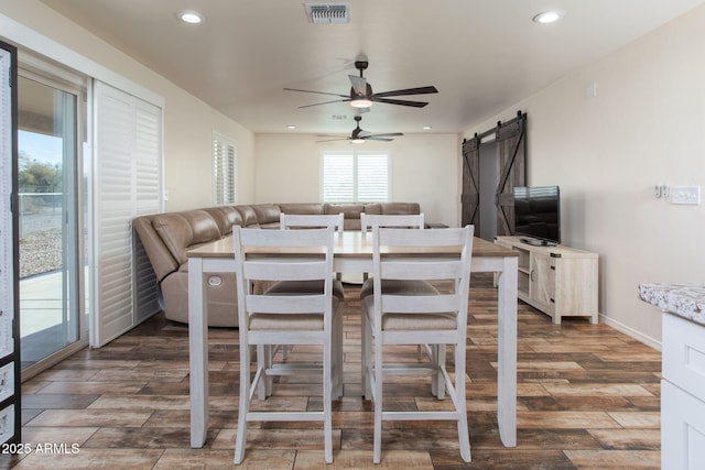 dining space featuring ceiling fan and a barn door