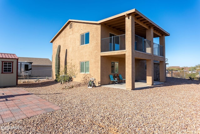 back of house with a storage unit, a balcony, and a patio