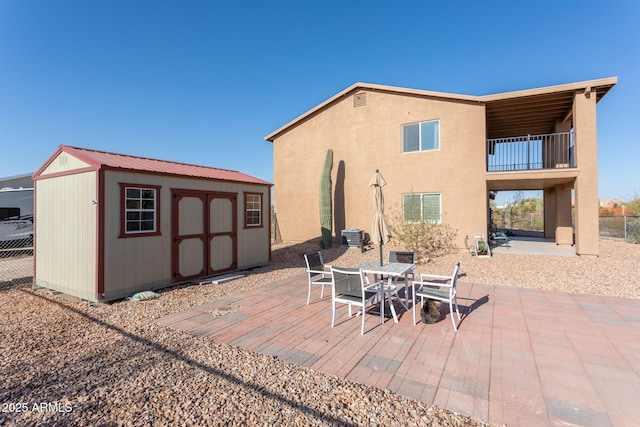 back of house with a balcony, a patio, and a shed