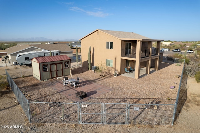 rear view of house featuring a patio area, a shed, and a balcony