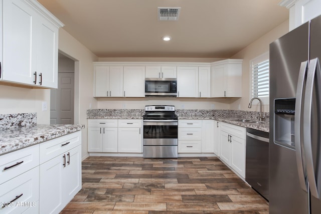 kitchen with dark hardwood / wood-style floors, stainless steel appliances, white cabinetry, and sink