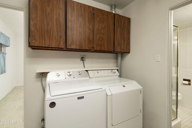 clothes washing area featuring cabinets and washing machine and dryer