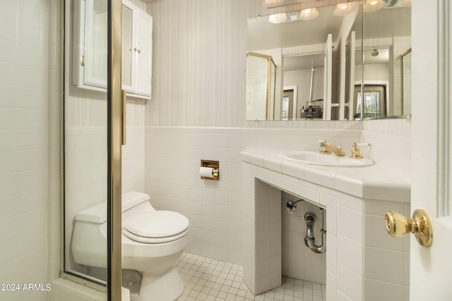 bathroom featuring tile patterned floors, walk in shower, toilet, sink, and tile walls