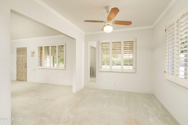 spare room with ceiling fan, crown molding, and light carpet