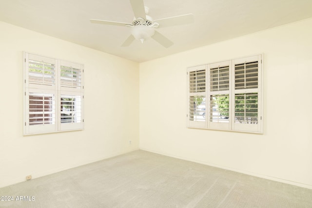 empty room featuring ceiling fan, a wealth of natural light, and carpet