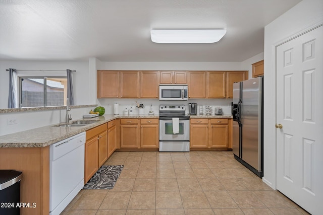 kitchen featuring appliances with stainless steel finishes, light countertops, a sink, and light tile patterned flooring