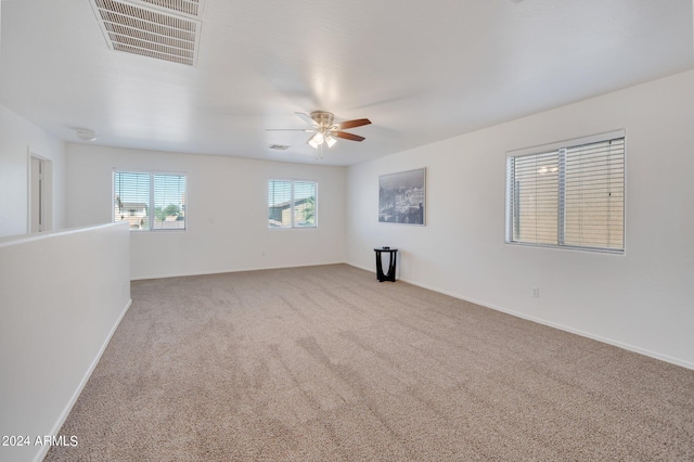 carpeted spare room with a ceiling fan, visible vents, and baseboards