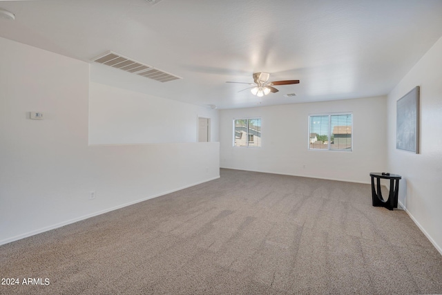 empty room featuring light colored carpet, visible vents, ceiling fan, and baseboards