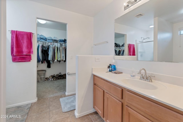 bathroom with tile patterned flooring, vanity, visible vents, a spacious closet, and a stall shower