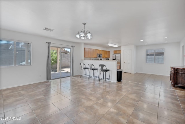 kitchen featuring open floor plan, stainless steel appliances, light countertops, light brown cabinets, and a chandelier