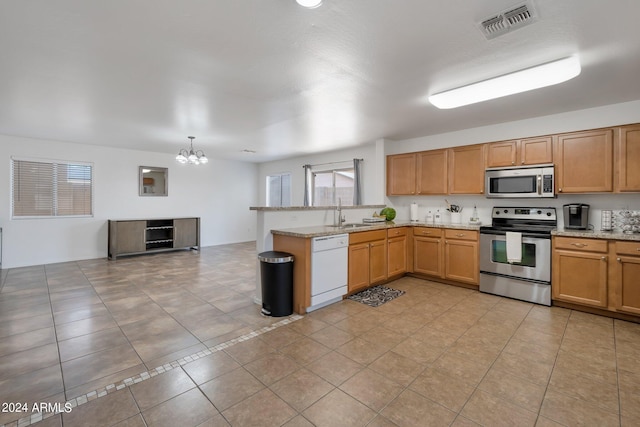 kitchen with light tile patterned floors, visible vents, a peninsula, light stone countertops, and stainless steel appliances