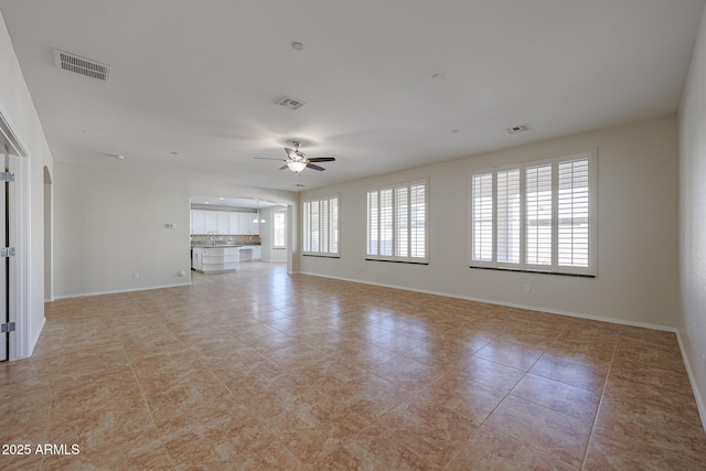 unfurnished living room featuring ceiling fan, sink, and light tile patterned floors