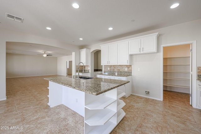 kitchen with sink, white cabinetry, ceiling fan, and dark stone countertops