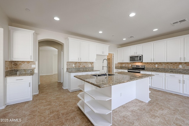 kitchen with white cabinets, appliances with stainless steel finishes, a kitchen island with sink, and sink