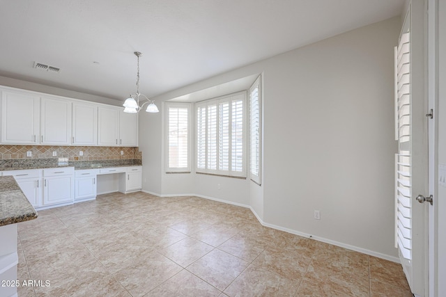 kitchen featuring tasteful backsplash, light tile patterned floors, white cabinets, a chandelier, and hanging light fixtures