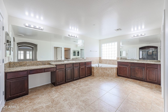 bathroom featuring tile patterned flooring, a relaxing tiled tub, a textured ceiling, and vanity