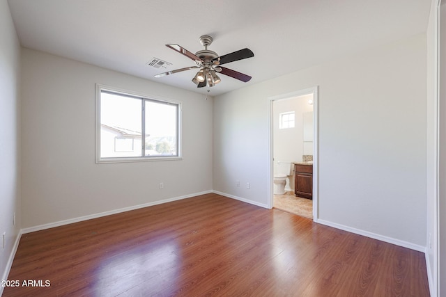 unfurnished bedroom with ensuite bath, ceiling fan, and wood-type flooring