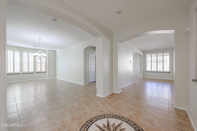 empty room with light tile patterned flooring and a chandelier