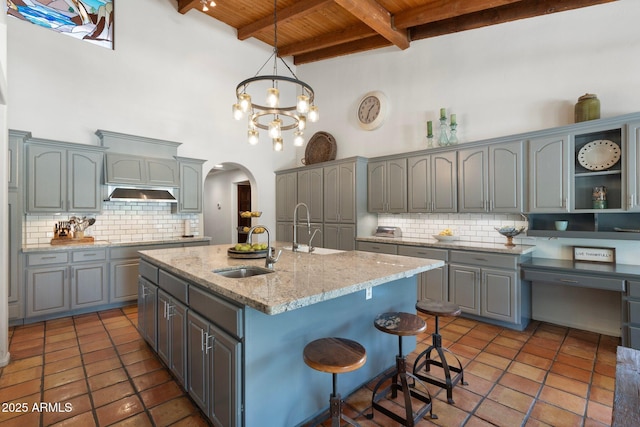 5540 E Mercer Ln, Scottsdale, AZ 85254 - kitchen featuring a wood ceiling with exposed beams, arched walkways, gray cabinets, decorative backsplash, and tile patterned flooring