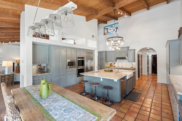 5540 E Mercer Ln, Scottsdale, AZ 85254 - kitchen featuring a wood ceiling with exposed beams, arched walkways, gray cabinets, decorative backsplash, and built in appliances