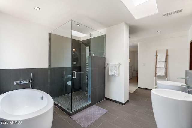5540 E Mercer Ln, Scottsdale, AZ 85254 - ensuite bathroom featuring a freestanding bath, a shower stall, tile patterned flooring, a skylight, and recessed lighting