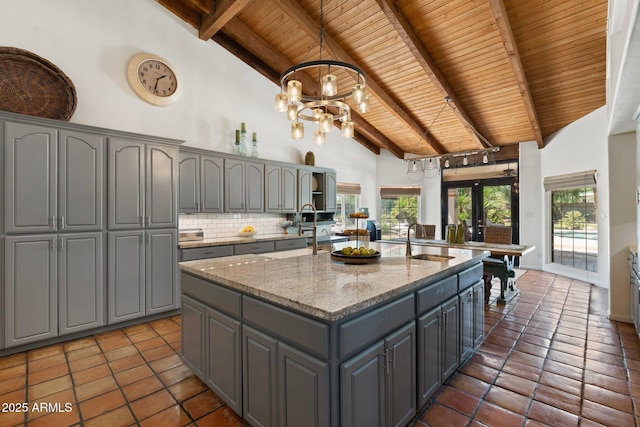 5540 E Mercer Ln, Scottsdale, AZ 85254 - kitchen with gray cabinetry, a wooden ceiling with exposed beams, a center island with sink, high vaulted ceiling, and light stone countertops