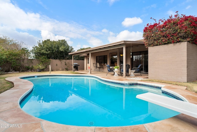 view of swimming pool with a patio and a diving board