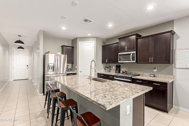 17344 W Red Fox Rd, Surprise, AZ 85387 - kitchen with dark brown cabinets, a sink, stainless steel appliances, light tile patterned floors, and visible vents