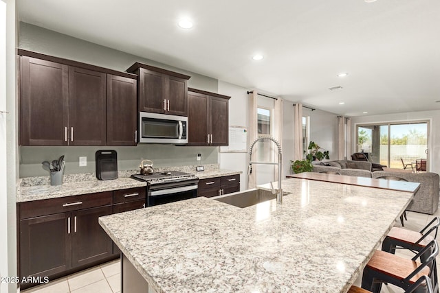 17344 W Red Fox Rd, Surprise, AZ 85387 - kitchen with dark brown cabinetry, a kitchen bar, appliances with stainless steel finishes, a sink, and recessed lighting