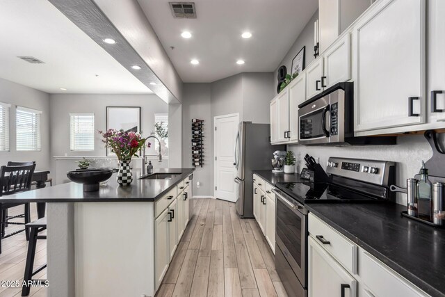 kitchen with a sink, visible vents, dark countertops, and appliances with stainless steel finishes