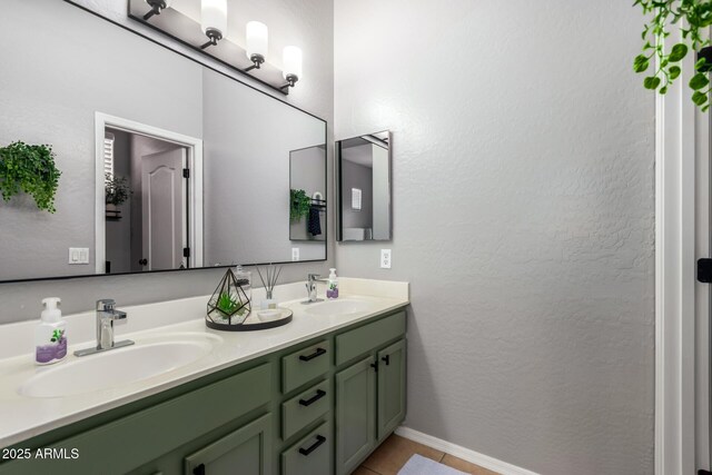 bathroom with a sink, baseboards, double vanity, and tile patterned flooring