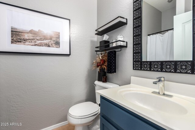 bathroom featuring toilet, vanity, and a textured wall