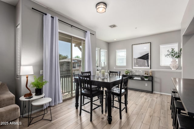 dining area with baseboards, visible vents, and light wood-type flooring