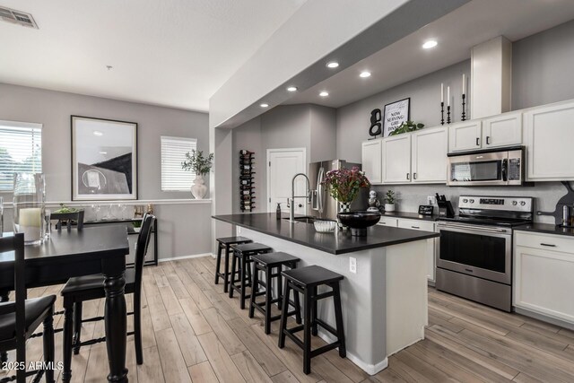 kitchen with dark countertops, visible vents, light wood finished floors, and stainless steel appliances