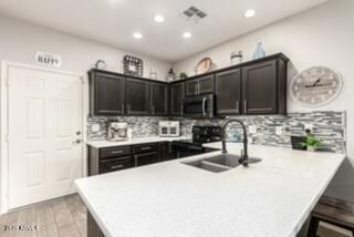 kitchen with sink, tasteful backsplash, range, kitchen peninsula, and light hardwood / wood-style floors